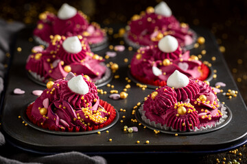 Sweet red cupcakes with golden sprinkles and cream.