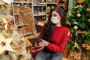 Christmas shopping in Corona time, woman wearing protective mask while shopping for Christmas presents 