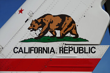 The California Republic (USA) Bear Flag logo is shown painted on the vertical stabilizer of a helicopter during the day.