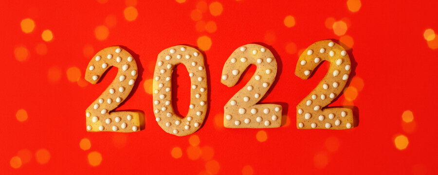 Happy New Year 2022. Christmas, winter holidays concept. Gingerbread cookies Number on traditional red background, fleyer, invitation, greeting card, banner, hard shadow