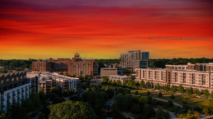 Fototapeta na wymiar a majestic shot of the cityscape with red, gray and white buildings surrounded by lush green trees with powerful clouds and gorgeous sky at sunset in Atlanta Georgia USA