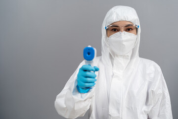 doctor in protective PPE suit scanning with infrared thermometer