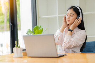 Young students use computers to study online. online education and learning Asian woman uses laptop technology while sitting at her desk and doing creative work. work from home concept