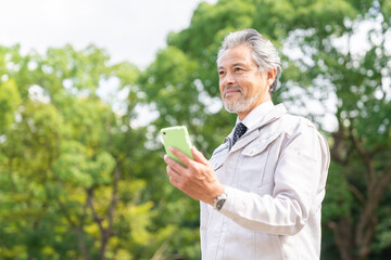 スマホを持つ作業服のシニア男性　ビジネス