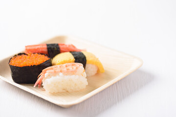 Nigiri sushi in a plate made from tree leaf on a white background is a cultural food of Japan, Asia.
