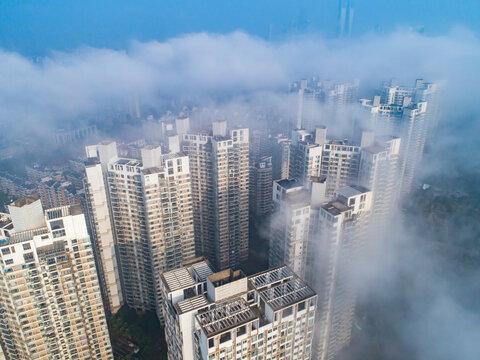 Heavy fog on the river and forest in calm morning weather. View of the residential buildings through the haze.morning urban landscape. Foggy City.Houses Protruding Through Fog. © hrui
