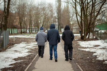 Three men walk down the road. Residents of Russia. Pensioners walk.