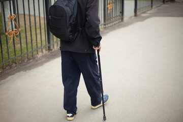 A man with a pole when walking. A pensioner in Russia walks down the street.