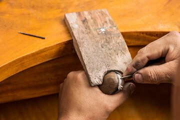 Hands of a male jeweller creating a silver jewel in a workshop
