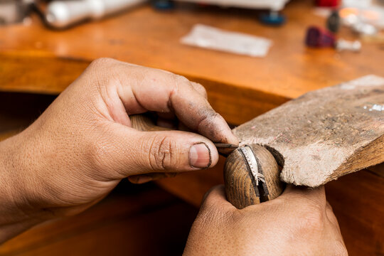 Close up view of the hands of an artisant working in a silver jewel in a workshop
