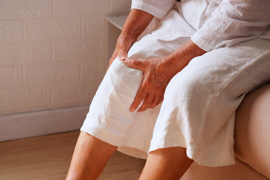 Elderly Asian woman holding a leg that is painful from varicose veins or from osteoarthritis, Various illnesses of the elderly and good health concept.