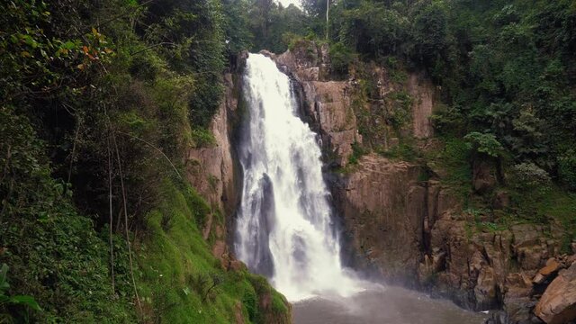 Beautiful waterfall in green wild tropical forest in National Park. Tropical mountain landscape of water waterfalls river flowing. Rocks with moss and roaring stream. Haew Narok waterfall in Thailand