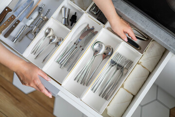 Top view closeup housewife hands tidying up cutlery in drawer general cleaning at kitchen