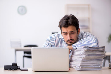 Young male employee and too much work in the office