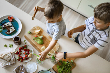 Top view children cooking fresh healthy breakfast with fruit, berries, vegetables on table kitchen