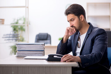 Obraz premium Young handsome employee working in the office