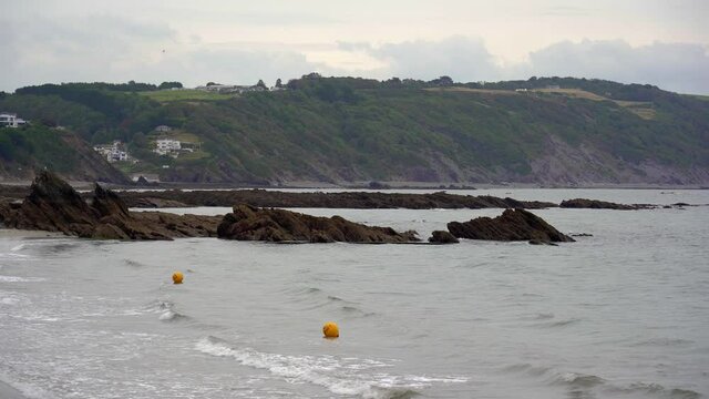 Yellow warning buoys bob up and down in the surf of East Looe beach in Looe, Cornwall, England, UK