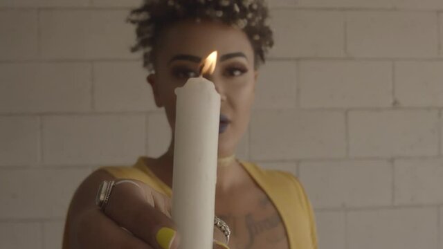 Black Beautiful Female With Yellow Shirt Holding White Lit Candle Near Camera. - Close Up