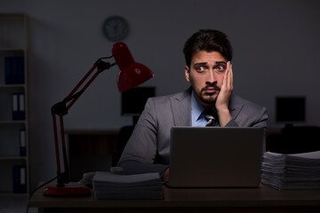 Young male employee working late in the office