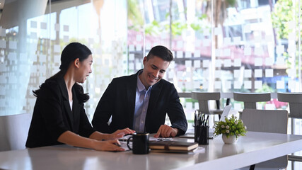 Happy business colleagues discussing project strategy together in modern office.