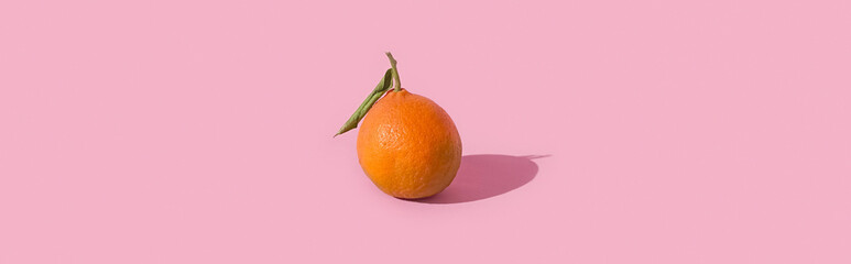 Fresh tangerine, clementine isolated on pink background with hard shadow. Pop art design, creative...
