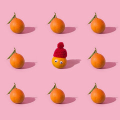 Winter Fruit seamless pattern of fresh tangerine, clementine isolated on pink background with hard shadows. One of fruits is in red hat and eyes