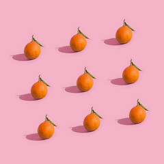 Fruit pattern of fresh tangerine, clementine isolated on pink background with hard shadows. Pop art design, creative summer concept. Citrus in minimal style.