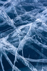 Natural ice with cracks. Blue thick ice with white cracks. Vertical.