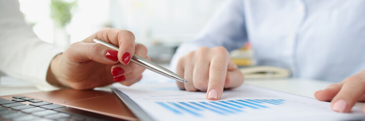 Female marketers discussing report in business graphs