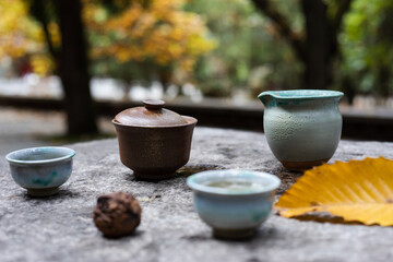 Close up on traditional Chinese tea cups and pottery on a stone table in a park