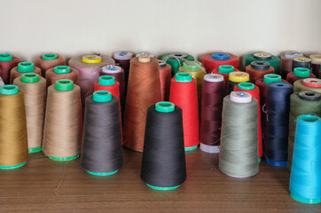 Colored spools of sewing threads stand in row