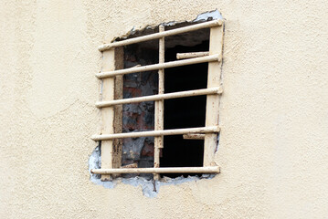 A window with a metal lattice in the prison building.