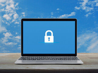 Padlock flat icon on modern laptop computer monitor screen on wooden table over blue sky with white clouds, Technology internet cyber security and safety online concept