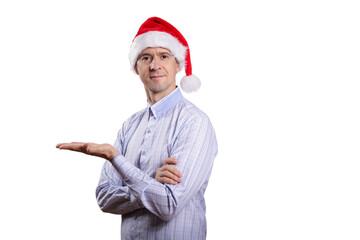 Adult confident man looks into the camera, palm of his hand parallel to the floor, dressed in casual clothes, a light plaid shirt, a New Year's cap. Isolated, homogeneous background