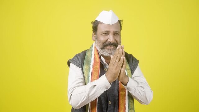 Indian Politician greeting by doing namaste - Concept of welcome gesture showing on yellow background.