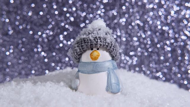 Christmas background. Snow falls. Happy snowman penguin standing in a winter christmas landscape. Merry christmas and happy new year greeting card. Penguin in a hat on a snowy background. 4k video