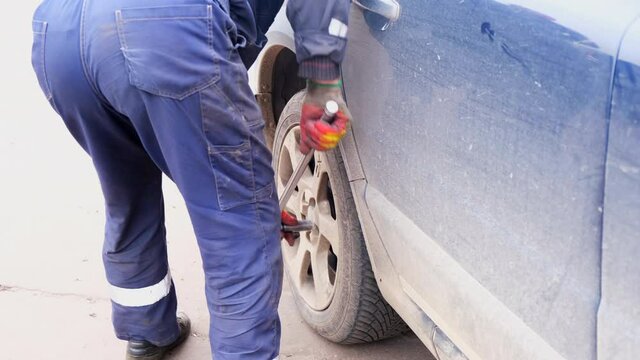 Man with effort fixes or spins a wheel on a car Volvo by hand, the process of removing or fixing a wheel with a hand tool at home, a mans job of replacing rubber on a car. Russia, Moscow, 10.16.2021