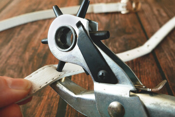 The process of manufacturing a leather belt by tanner. Puncture holes in the strap using a punch....