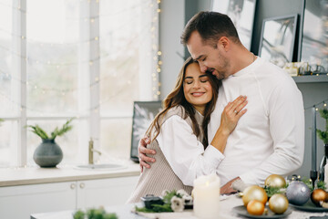 Young loving couple having good time at Christmas morning in kitchen