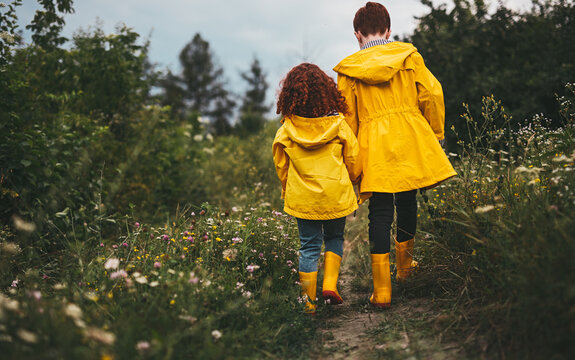 Ginger siblings in yellow raincoats and runner boots in field