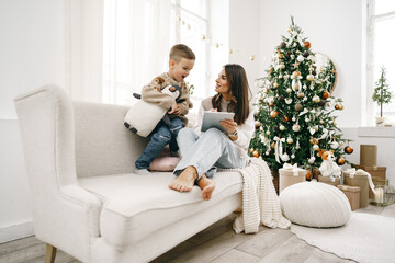 Portrait of a smiling young woman with her son using digital tablet on winter holidays