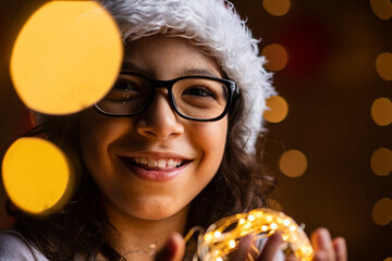 Retrato de un joven adolescente con vestimenta navideña con luces cálidas en sus manos