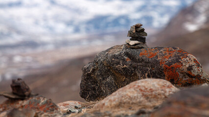 The statue of laying out stones against the background of snowy mountains is deeply in the tourism of Russia