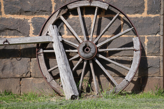 old wagon wheel against bluestone wall