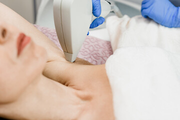 Fototapeta premium Young woman having underarm laser epilation in modern beauty salon