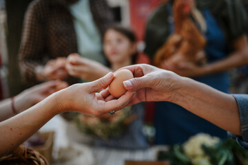 Close up of woman buying organic egg outdoors at local farmers market.