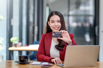Pretty young Asian woman using laptop computer and using credit card for online shopping.