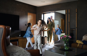 Happy young family with two children enetring room at luxury hotel, summer holiday. - obrazy, fototapety, plakaty