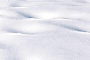 Snowy background of fluffy white snow shining in the sun. White natural background. Winter texture