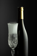 Bottle and glass of champagne on a black background.